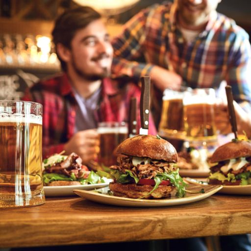 Two people in a cozy pub enjoy burgers and large mugs of beer in restaurants and bars in franklin tn. The atmosphere is lively and inviting, with a focus on hearty, satisfying food.